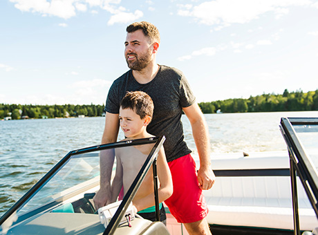 Father and son boating on a lake in a new boat purchased with funds from a recreational loan.