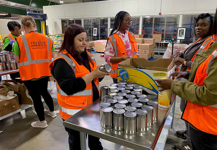 A group of Landmark associates are volunteering at a Feeding America warehouse.