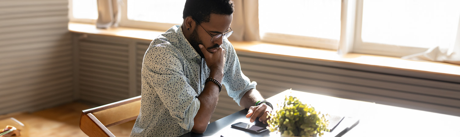 A member at home gazes at their phone, contemplating whether the message they received might be a scam or not.