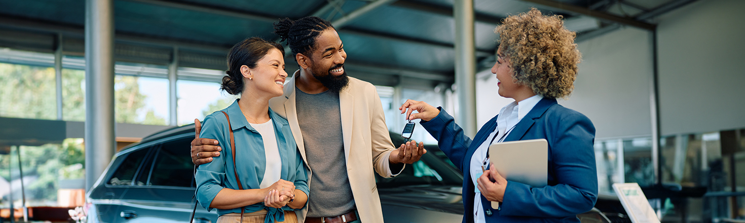 Couple receiving keys to their new car