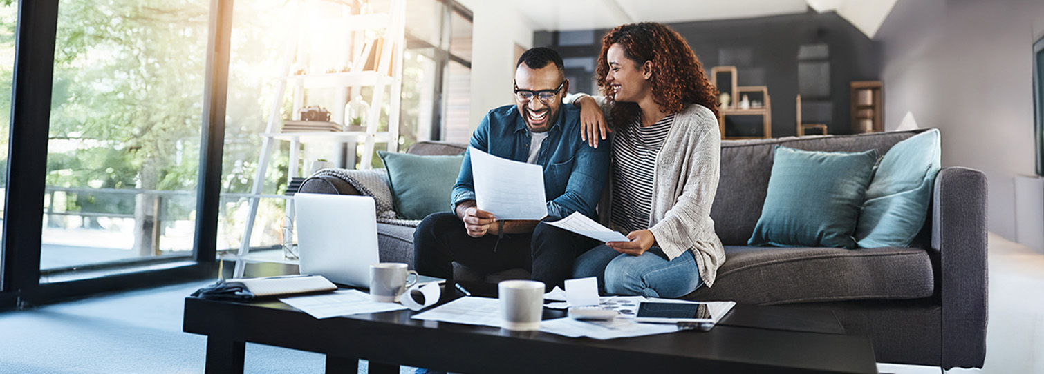 Joyful couple relaxing on sofa and celebrating their retirement plans and financial success