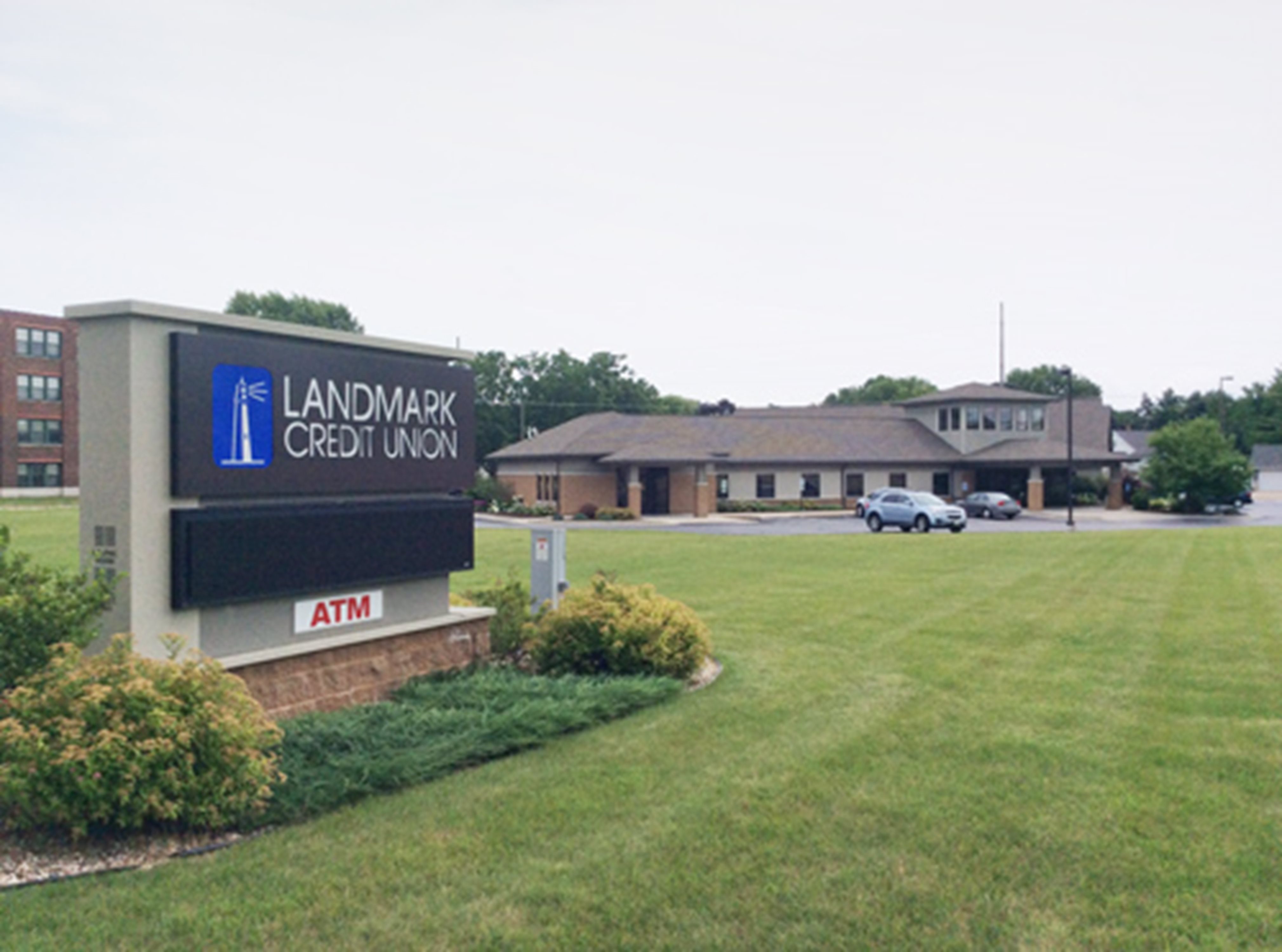 An exterior of Beaver Dam branch - brown building with large grassy lawn in foreground with Landmark Credit Union sign. 
