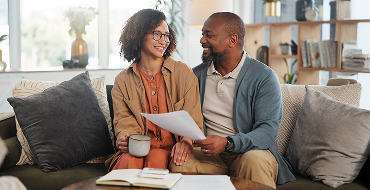 Couple sitting on couch looking through financial documents