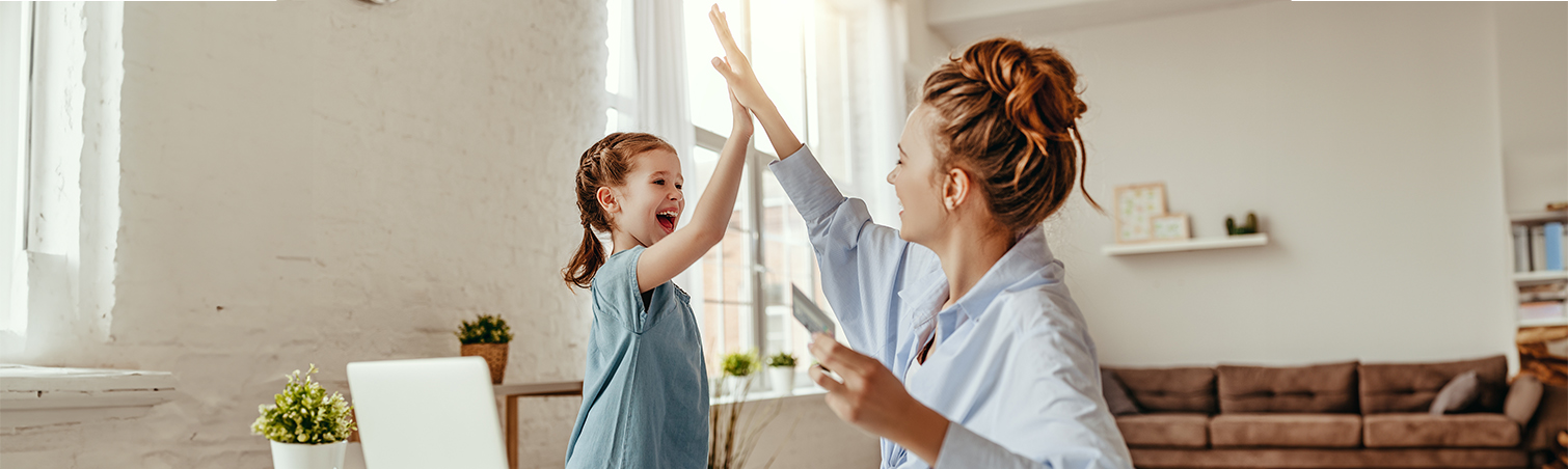 A mother is high-fiving her daughter in their kitchen.