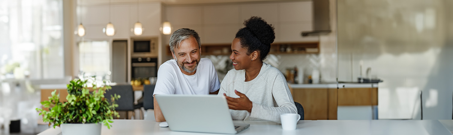 Happy couple sitting at a table in their home, discussing their retirement plans.