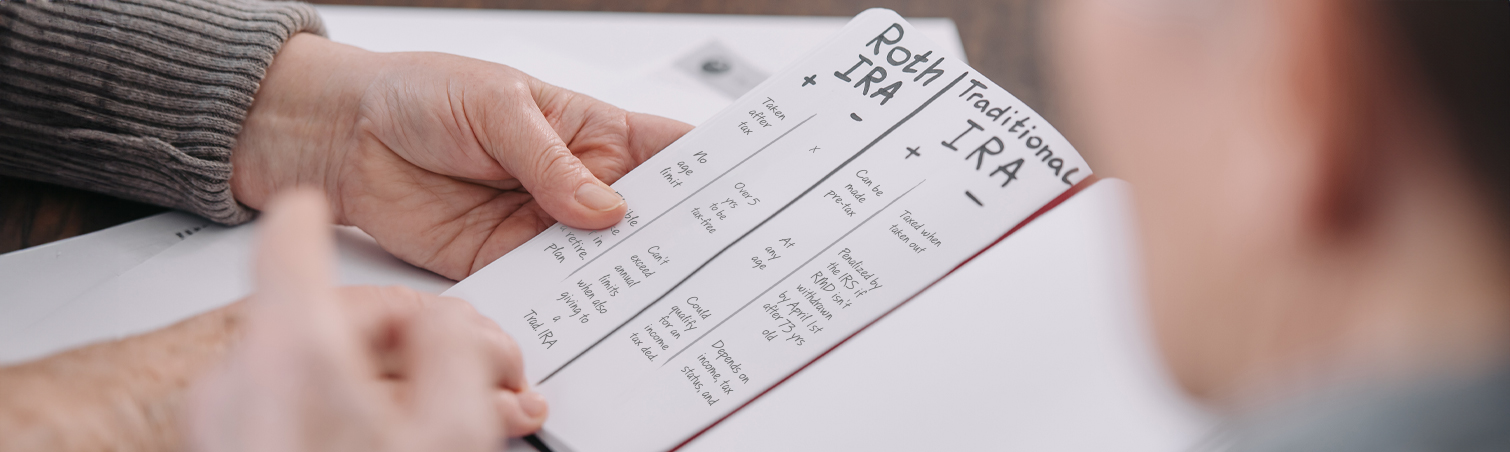 Person writing down a comparison chart between Traditional and Roth IRAs
