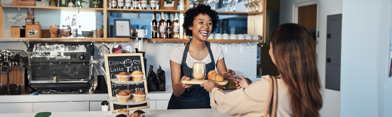 A smiling member is working the counter at a summer job in a bakery.