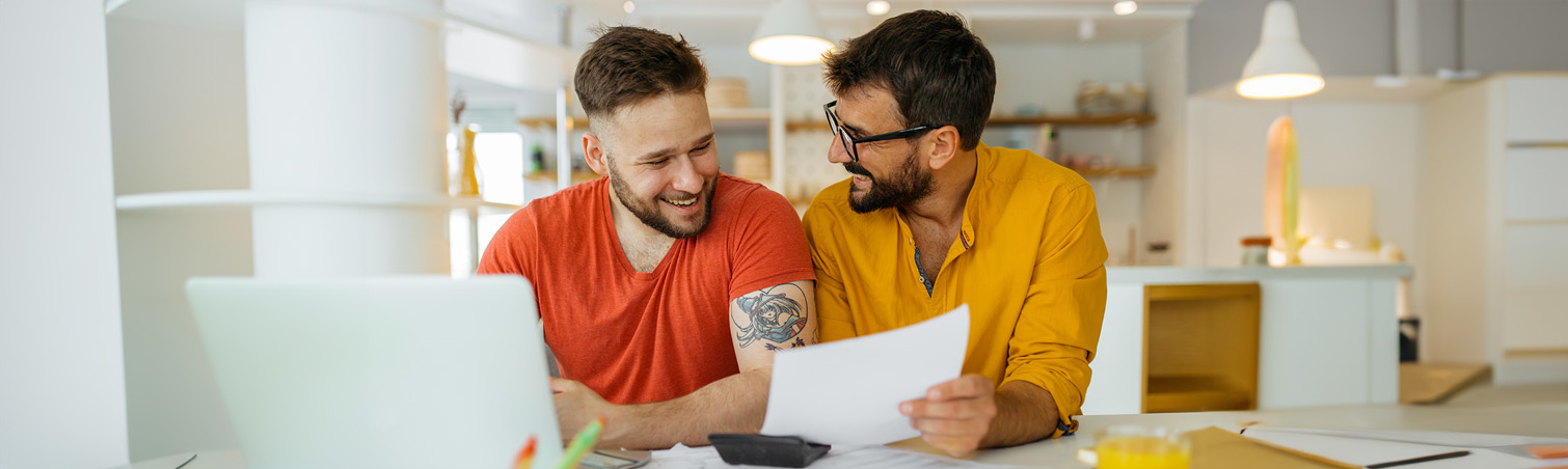 A couple sits at the table in their home as they look over guides on merging their accounts. 