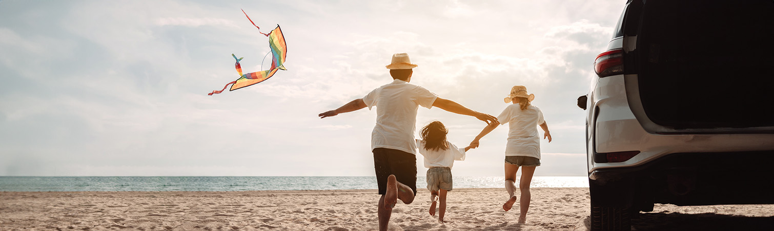 A happy family is enjoying their time flying a kite on the beach.