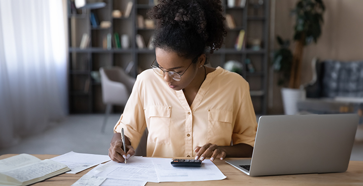 Woman sitting at a desk with laptop and filling out documents