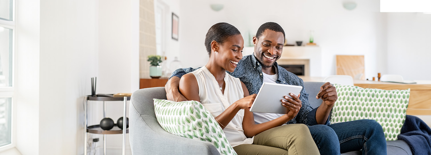 Couple sitting on couch looking at a tablet