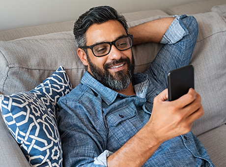 Landmark member sitting on couch exploring IRA account options on their mobile device