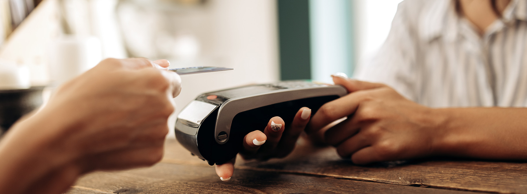 Customer presenting credit card for payment at pos machine.