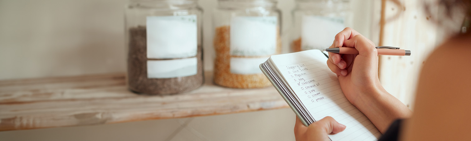 Person writing a list in a notebook for personal money management.