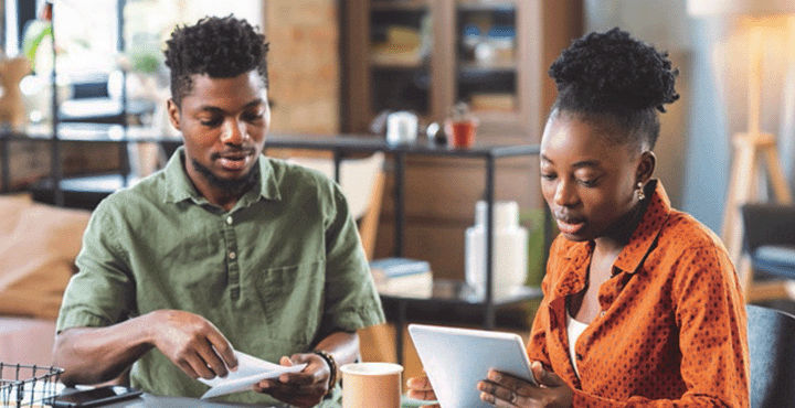 A couple in their homes sit together at a table looking over paperwork during tax season.