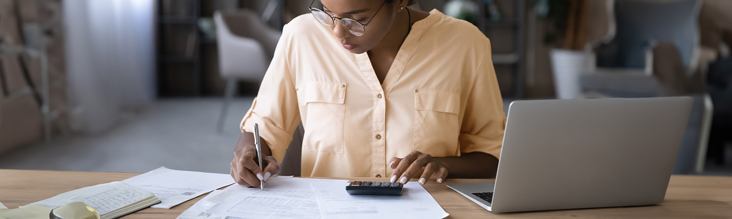 Woman sitting at a desk with laptop and filling out documents