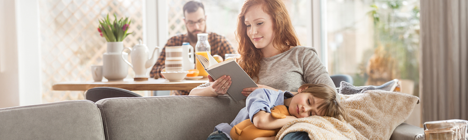As her child cuddles with her on the couch, a mother conducts research on home hazard prevention.